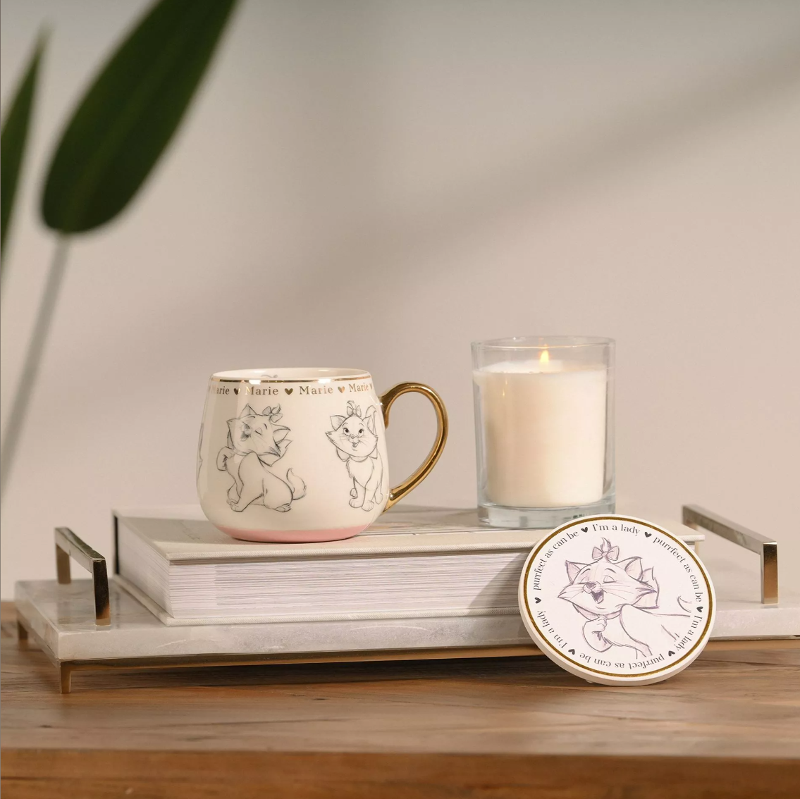 Mug, candle, and coaster with character design on a wooden surface