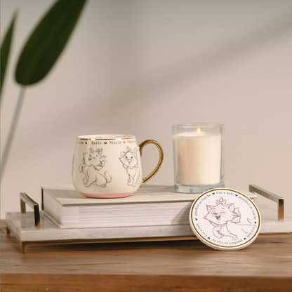 Mug, candle, and coaster with character design on a wooden surface