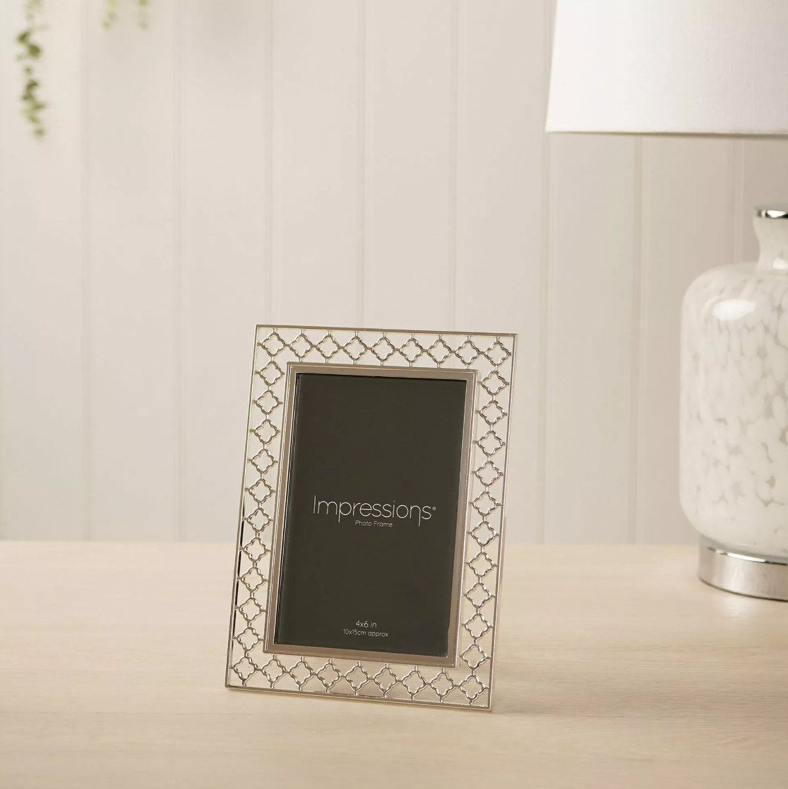 Decorative photo frame with 'Impressions' branding on a table.
