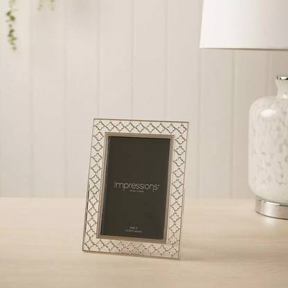 Decorative photo frame with 'Impressions' branding on a table.