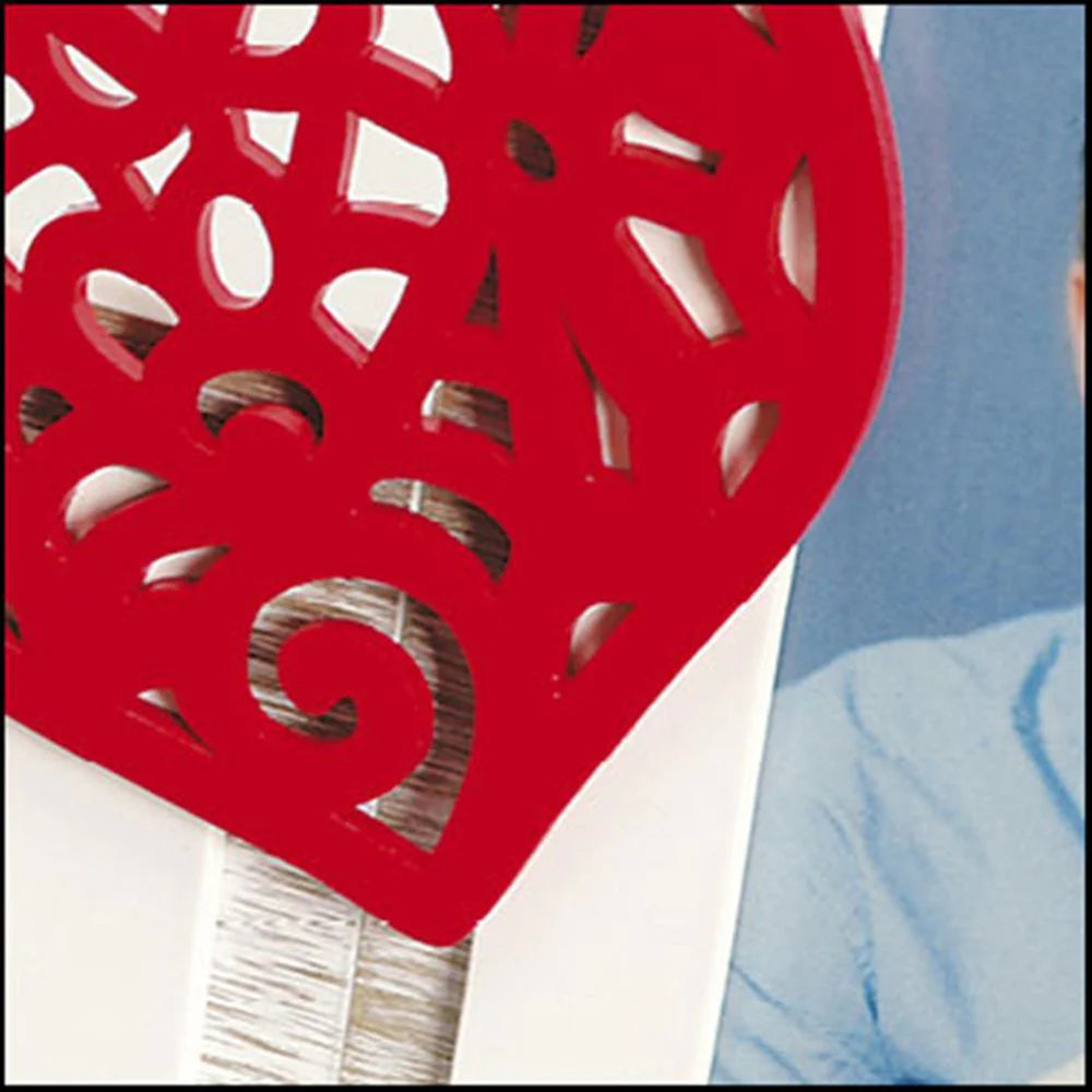 Red decorative heart-shaped object on a white surface with a blue background