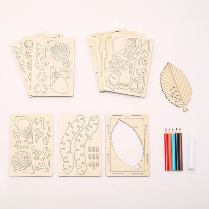 A leaf-shaped wooden DIY craft kit laid out on a white background, including multiple engraved wooden template pieces, a large leaf-shaped outline piece, colored pencils, and a paintbrush.