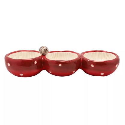 A three-compartment ceramic bowl set in glossy red with white polka dots and cream-colored interiors, featuring a small hedgehog figurine on the left divider, shown against a plain white background.