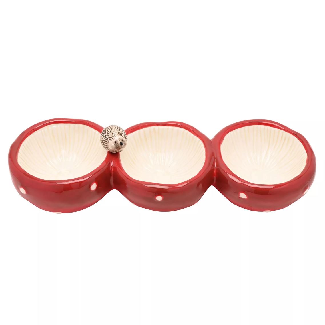 A three-compartment ceramic bowl with a glossy red exterior, cream-colored ribbed interiors, small white polka dots, and a small hedgehog figurine perched on the centre divider, shown against a plain white background.
