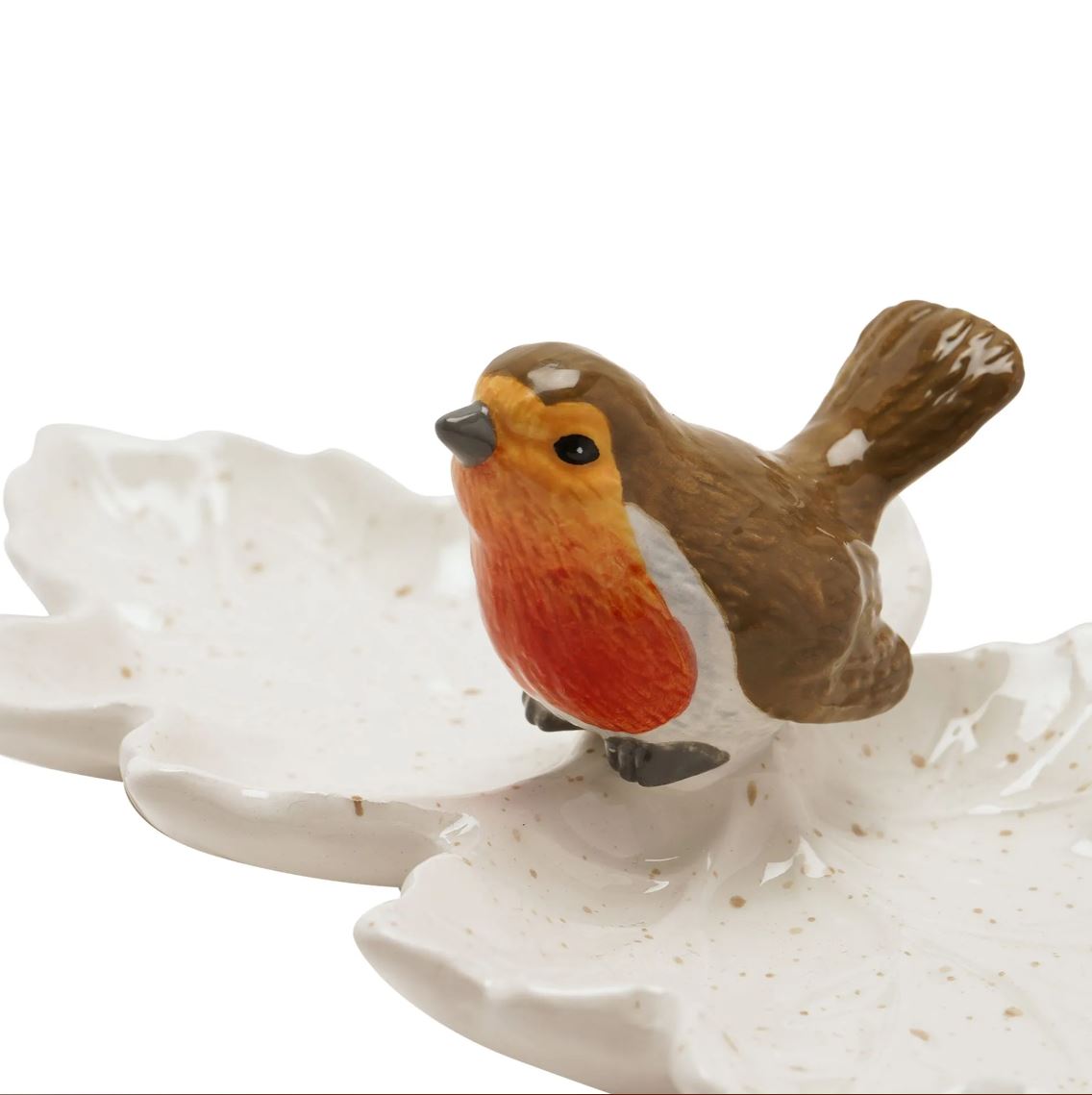 A ceramic robin bird figurine perched on a white leaf-shaped dish, photographed against a plain white background.