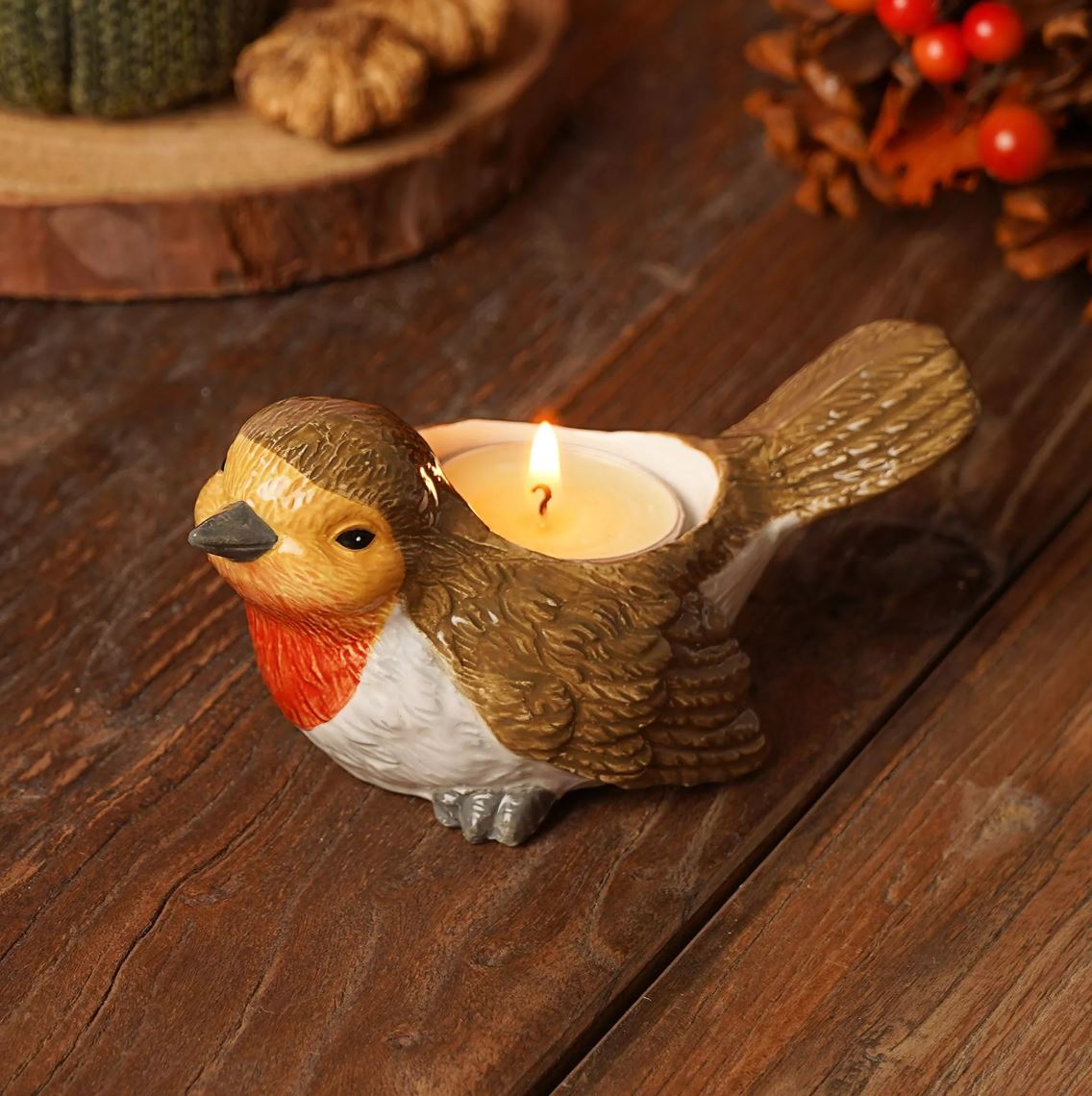 Bird-shaped candle holder with a lit candle on a wooden surface