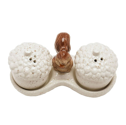 A ceramic salt and pepper shaker set featuring two acorn-shaped containers with textured cream glazes and a small brown squirrel figurine in the center, all on a matching base against a white background.