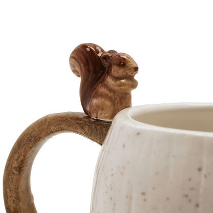 Close-up of a ceramic mug with a sculpted squirrel handle and a cream-colored speckled body, shown against a white background.