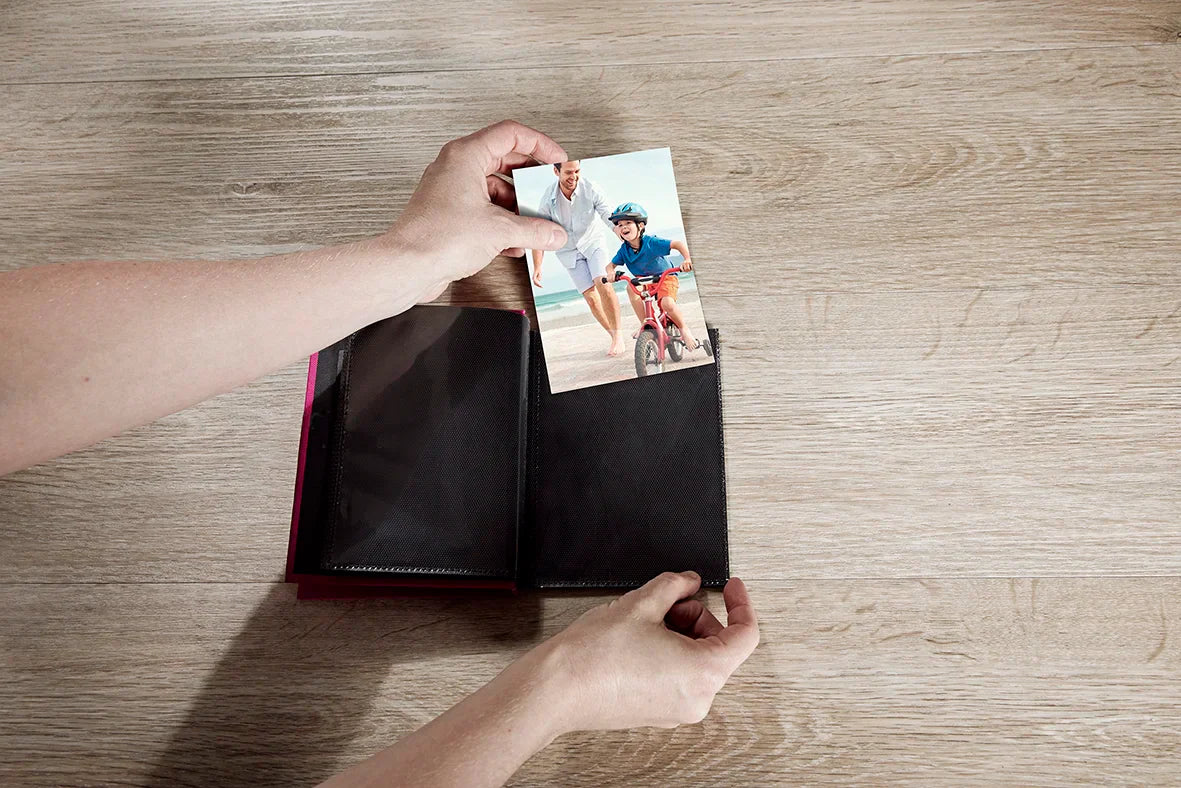 Person opening a photo album to reveal a couple on a bicycle in a photo