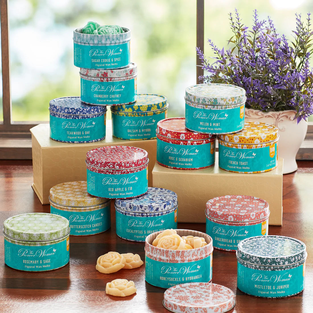 Assorted tins of Peter Wren products on a wooden surface with a window and plant in the background.
